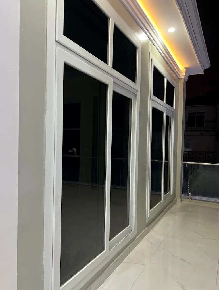 White sliding windows with top lights enclosing a lit balcony at night