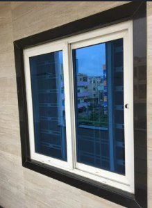 White sliding window with blue tinted glass and a dark stone surround