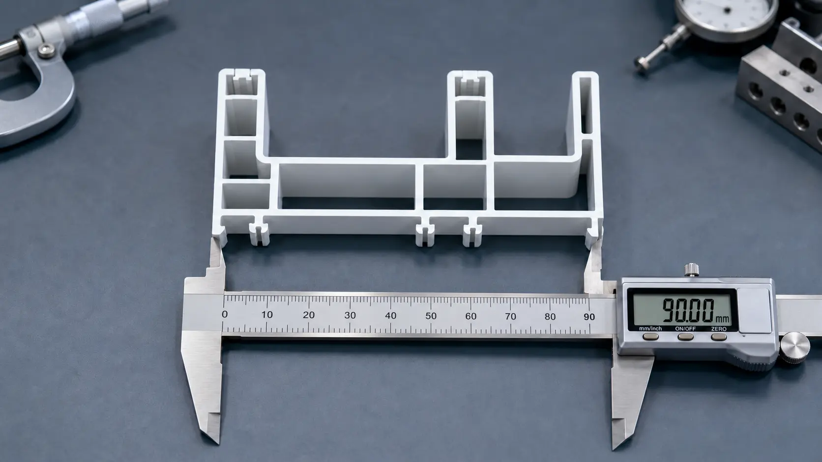 Cut section of a 90 mm white UPVC sliding frame measured with a digital caliper